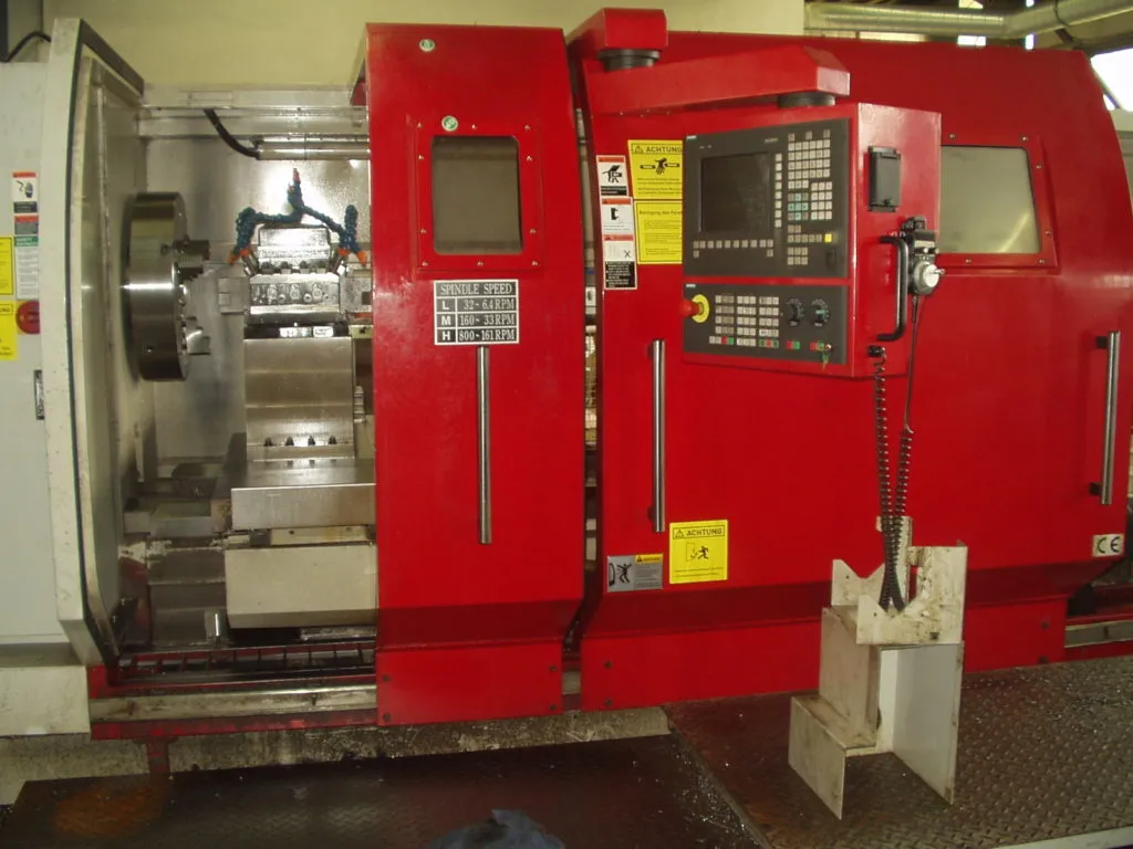 Rote CNC-Drehmaschine mit geöffneter Schutztür, Spannfutter, Werkzeugrevolver und Bedienpult.